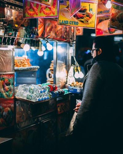 夜间站在食品车前的穿着外套的男人